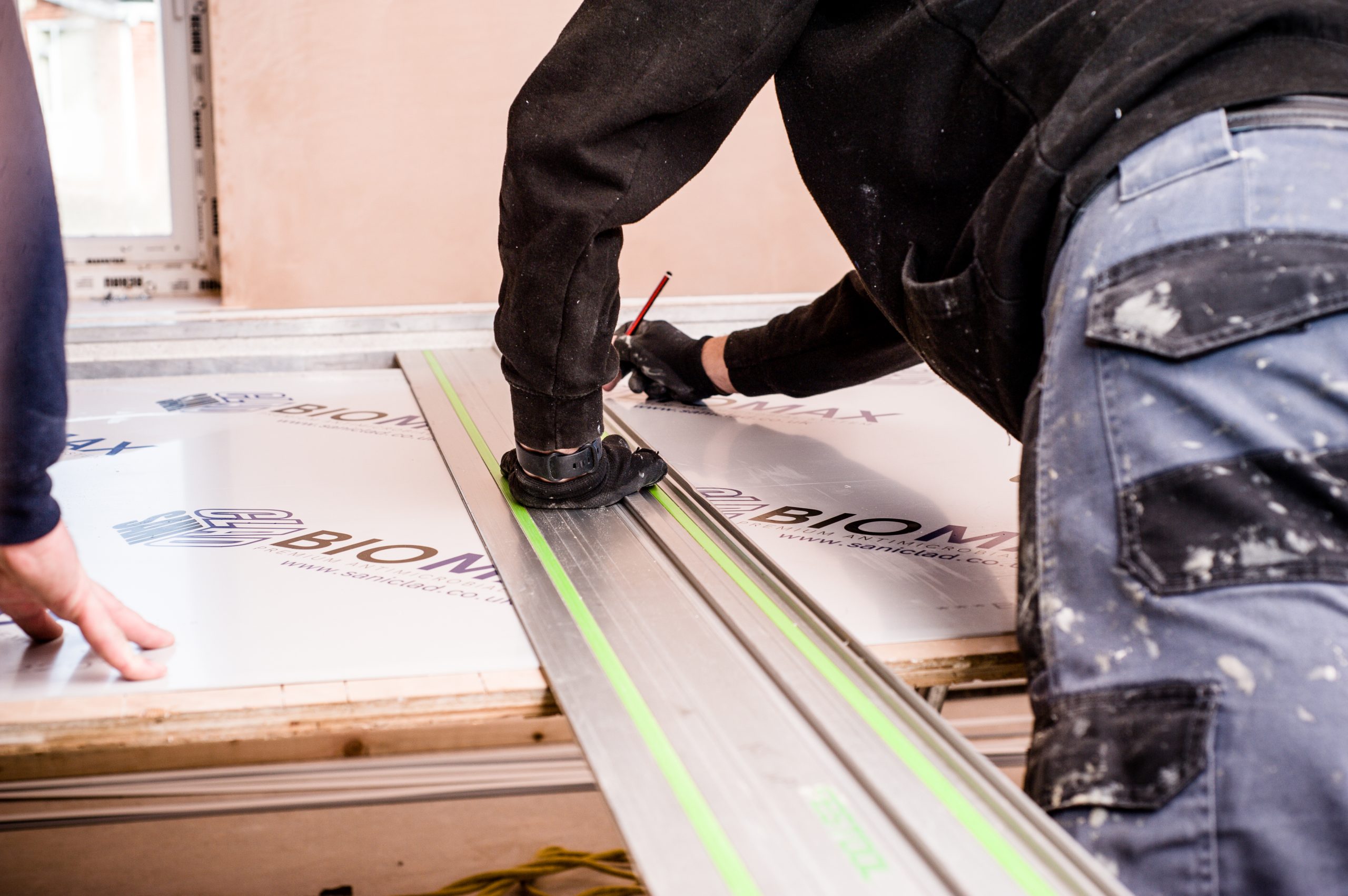 Worker applying BIOMAX™ Hygienic Wall Cladding, showcasing durable and hygienic wall cladding technology.